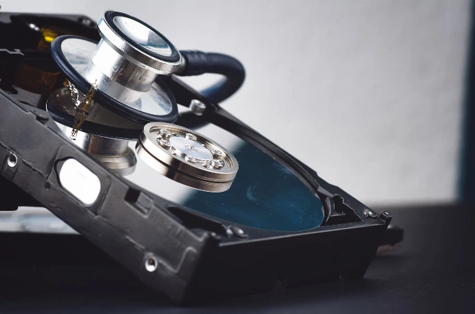 Professionelle Datenrettung von KNT Solutions - Bild einer Festplatte, die mit Hilfe eines Stetoskops untersucht wird